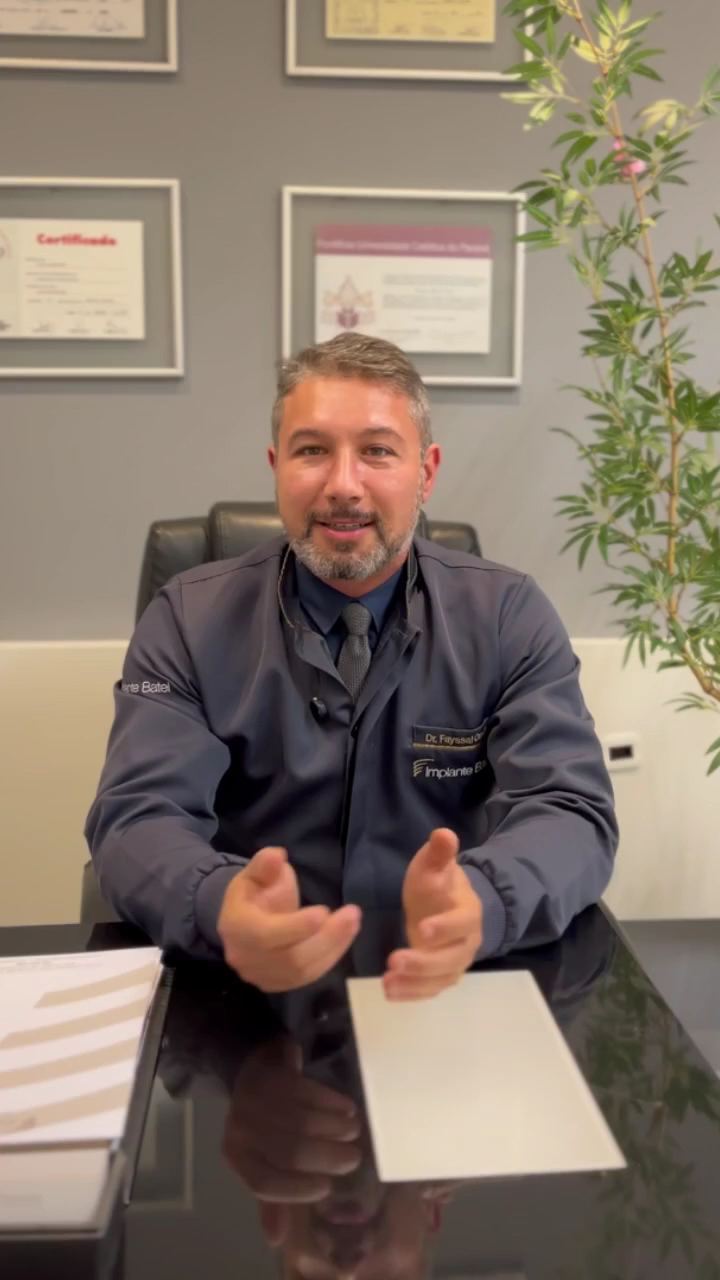 Dr. Fayssal Ahmad Omar sorrindo, sentado à mesa do consultório