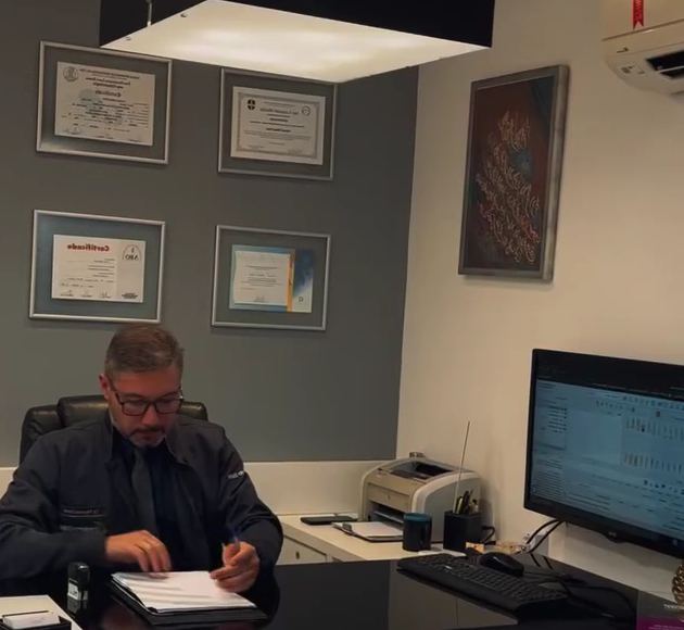 Dr. Fayssal à mesa do consultório, com certificados na parede